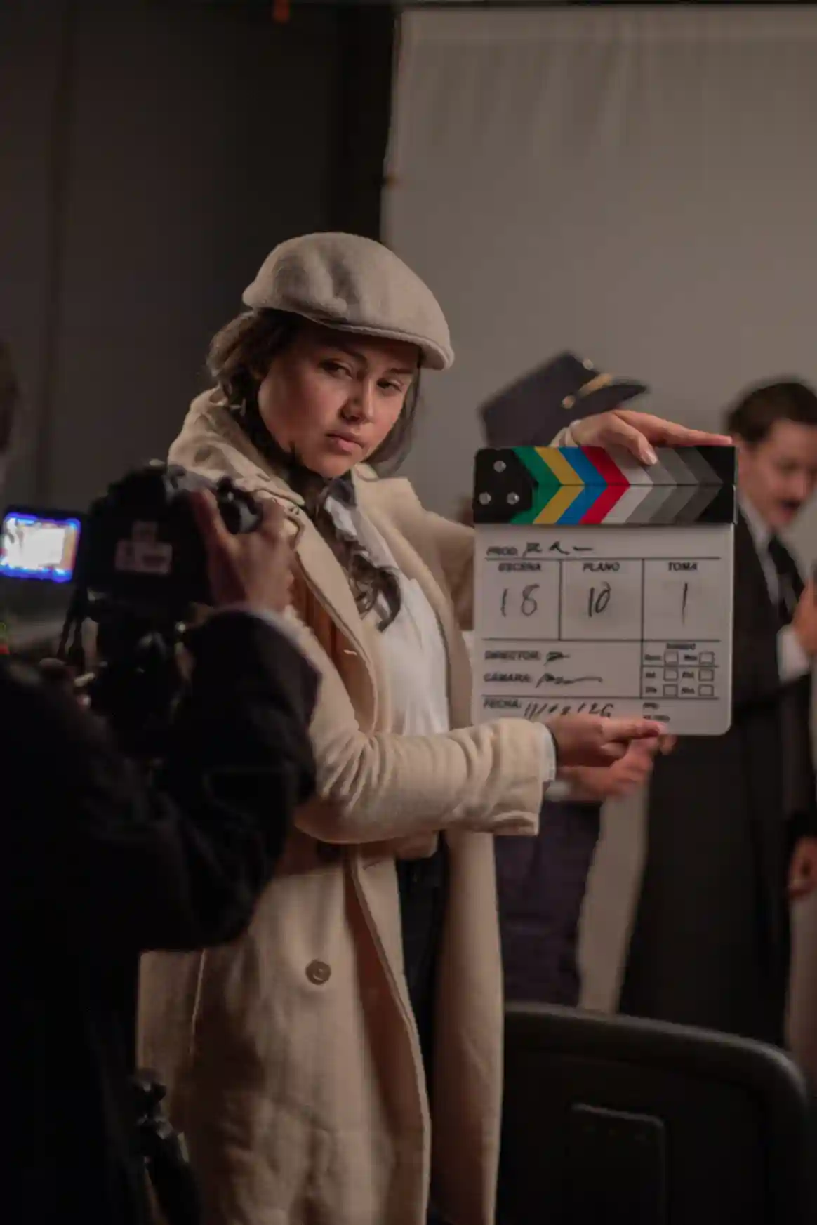 Mujer sosteniendo una claqueta mientras filma una escena en un set de grabación.