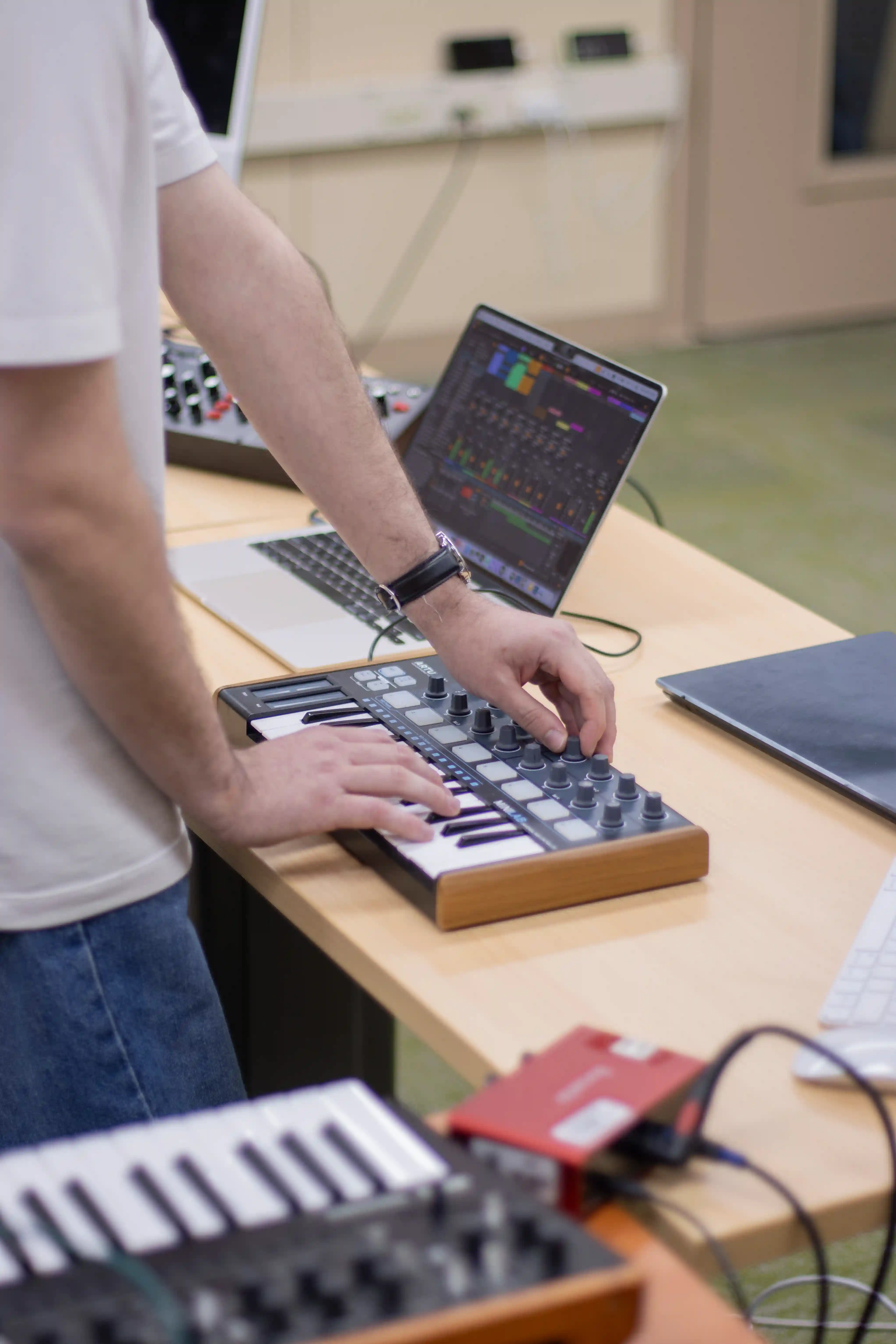 Hombre tocando un teclado, concentrado en la música que está creando.