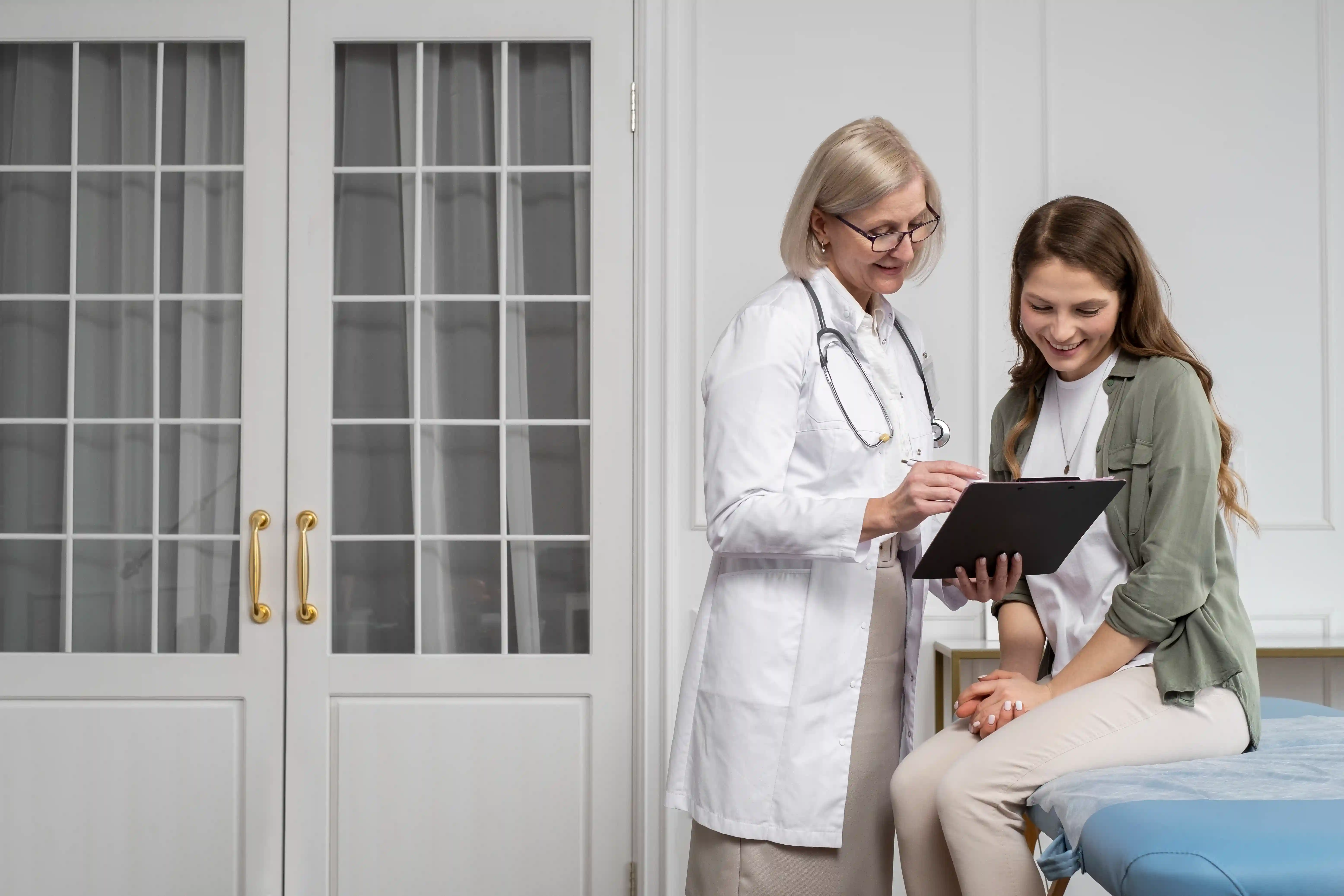 Una médica amigable y su paciente revisan información de salud juntos en una tableta digital dentro de un consultorio