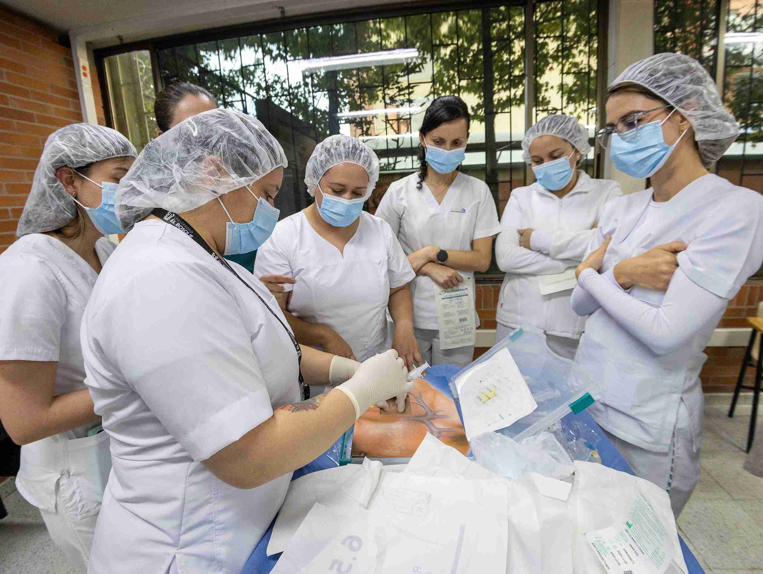 Un grupo de enfermeras en uniformes blancos atiende a un paciente en una sala de hospital.
