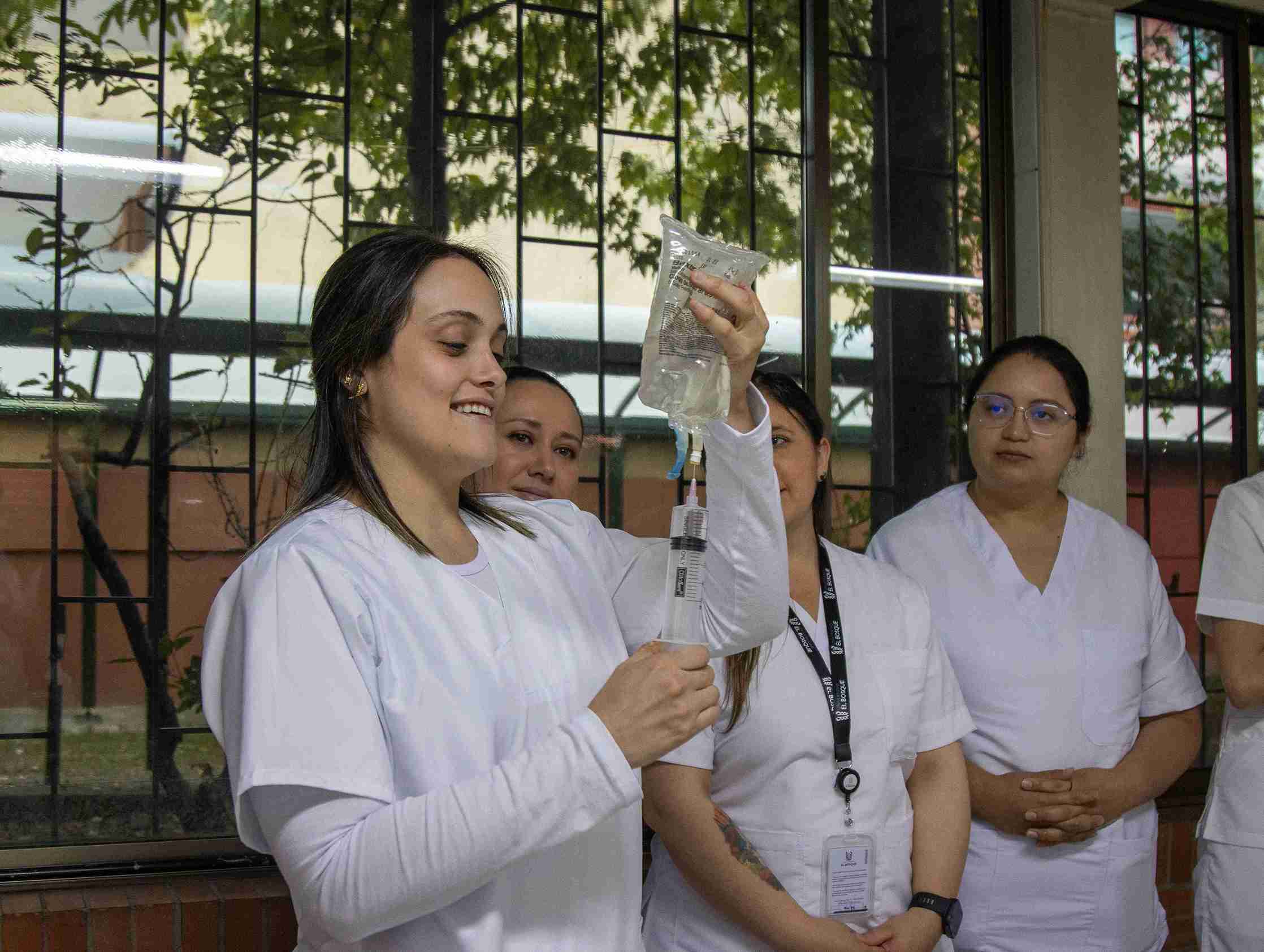Una enfermera sostiene una jeringa mientras otros observan atentamente la situación.