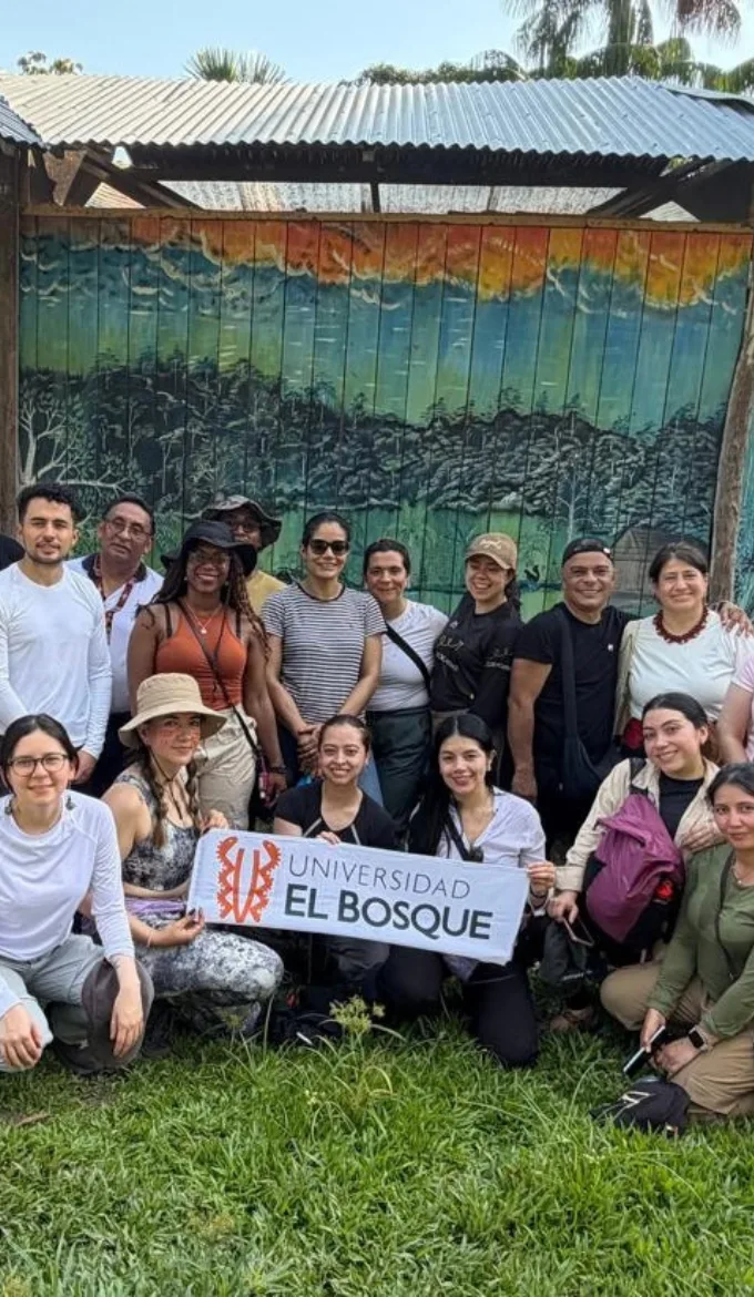 Grupo de personas sonriendo y posando frente a un mural colorido en un entorno urbano.