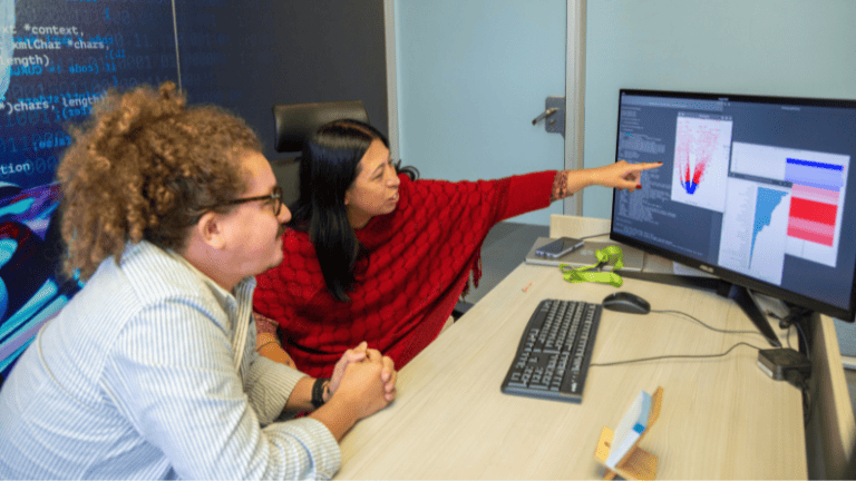 Una mujer y hombre observan atentamente la pantalla de una computadora.