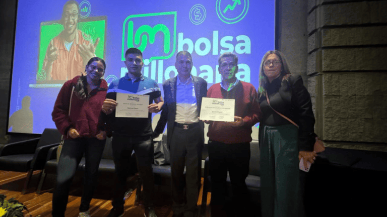 Cuatro personas sosteniendo certificados frente a una pantalla, sonriendo y celebrando su logro.