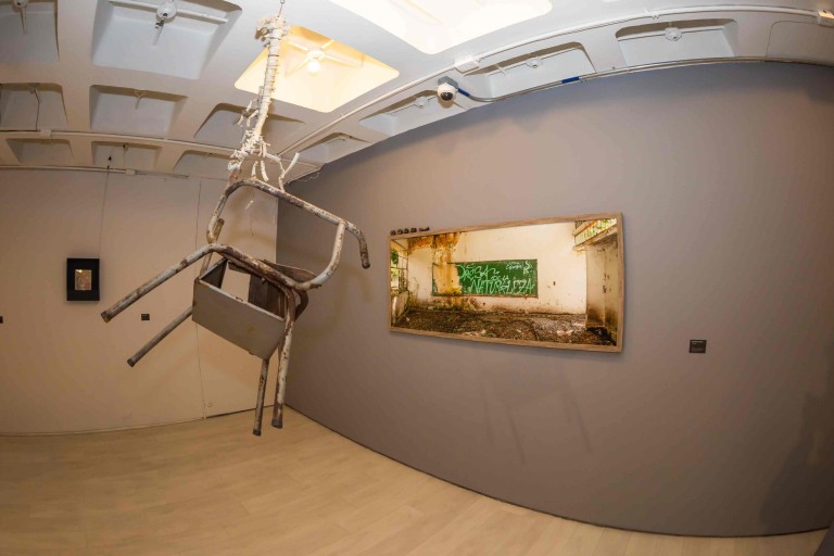 Instalación artística con silla suspendida en la exposición AFUERA en el Centro Colombo Americano de Bogotá