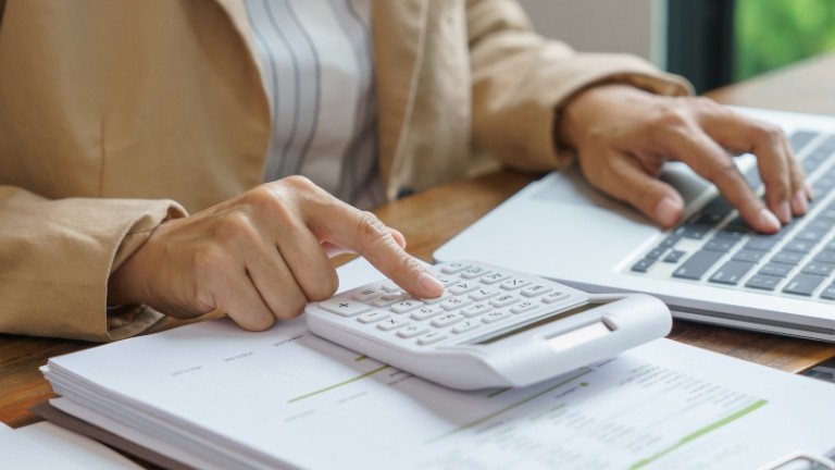 Persona usando una calculadora y un computador portátil para calcular su declaración de renta