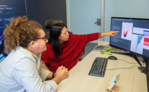 Una mujer y hombre observan atentamente la pantalla de una computadora.
