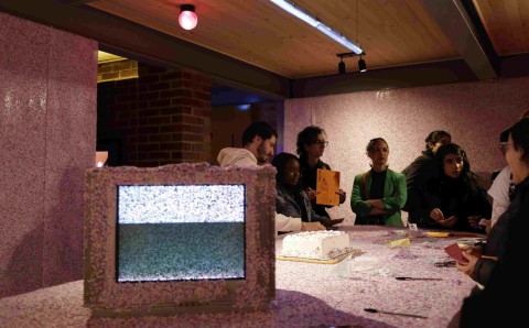 Publico interactua con instalacion artistica con confeti, monitor y torta durante la exposicion NOOB en la Universidad El Bosque.