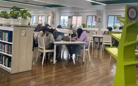Estudiantes de la Universidad El Bosque en el Laboratorio de Lectura de la Biblioteca Juan Roa Vásquez, rodeados de libros y tecnología.