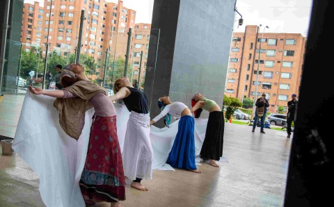 Vista general de la intervención artística colectiva sobre la recuperación del Río Bogotá, con performance en primer plano y mural panorámico al fondo, en la Universidad El Bosque.