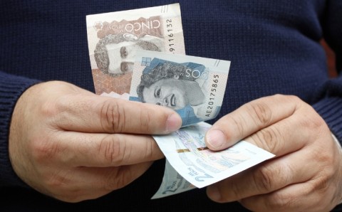 Persona sosteniendo billetes de pesos colombianos para pagar su declaración de renta