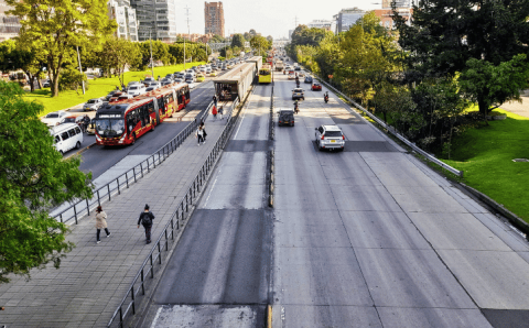 Estación de TransMilenio en Bogotá, con buses, pasajeros y tráfico en la vía