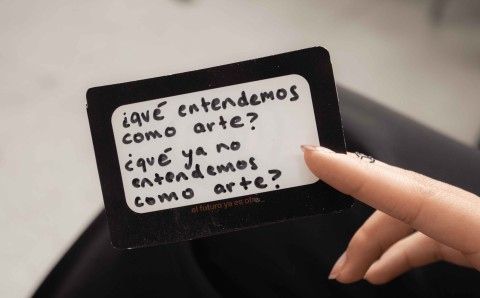 Estudiante sostiene una tarjeta con la pregunta "¿qué entendemos como arte? ¿qué ya no entendemos como arte?"