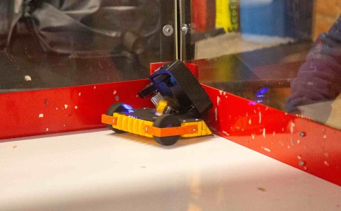 Robot de guerra de colores amarillo y negro dentro de la jaula de combate del Torneo RHA Robotics 2026.